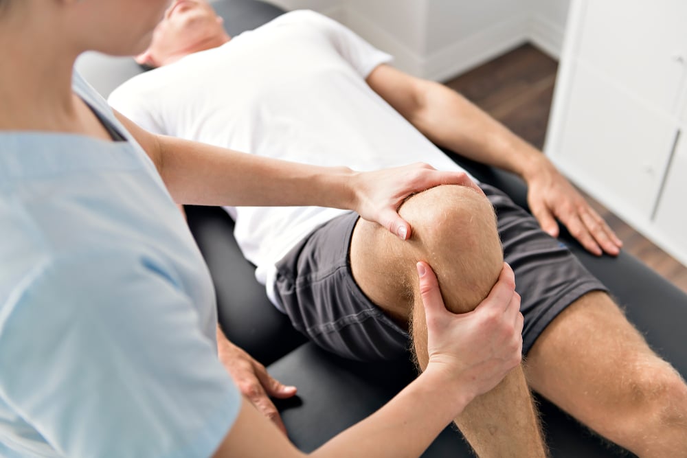 Physical therapist helping patient with knee pain