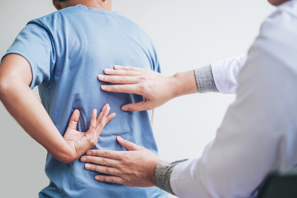 Osteopath or chiropractor treating young man for back pain