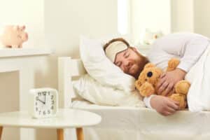 Man sleeping on mattress with teddy bear