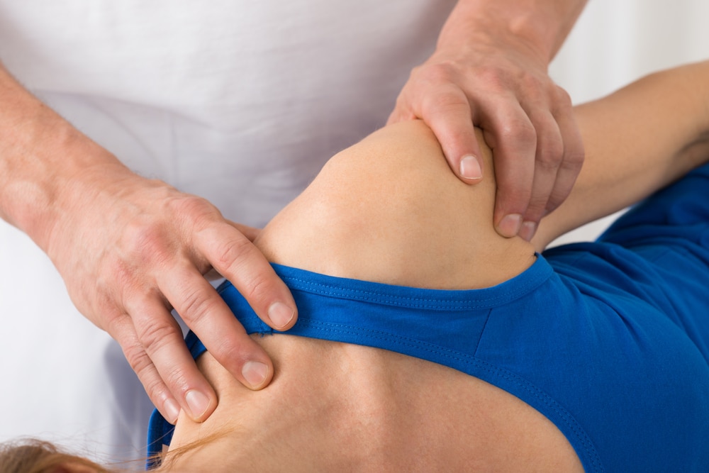Person receiving massage from chiropractor for frozen shoulder